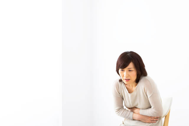 胃の痛みを感じる女性